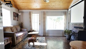 Een gezellige woonkamer met houten plafond, een bank, een salontafel en een eettafel.