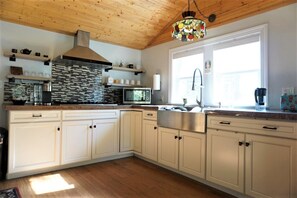 Une cuisine moderne avec des armoires blanches, une hotte de cuisinière en acier inoxydable, un four à micro-ondes et une grande fenêtre offrant une belle vue.