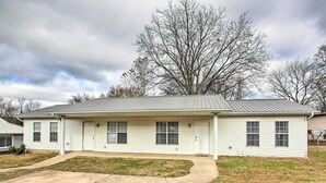 A single-story house with a front porch, a driveway, and a large tree in the background.