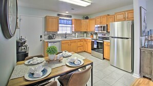 A modern kitchen with wooden cabinets, stainless steel appliances, and a dining area with a table set for four.