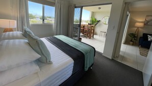 A hotel room with a bed, a view of the outdoors, a dining area, and a bathroom. - City Stadium Apartment Riverfront 38 (Townsville)