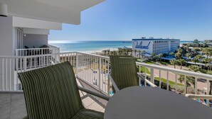 A balcony with a view of the beach and a hotel named 'The Island'. - Remodeled Beachfront 🐠🦀 Destin West's Best 😎😎 Beach Service Inc ⛱️⛱️NEW EVERYTHING (Fort Walton Beach)