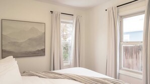 Ein Schlafzimmer mit Bett, Fenster und einem Bild an der Wand.