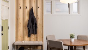 Ein Zimmer mit einer Wand aus Holzlatten, einer Bank, einem runden Tisch mit Stühlen und einer Pendelleuchte.