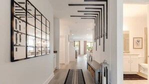 Um corredor moderno com divisória de vidro, tapete listrado em preto e branco e design minimalista com linhas pretas no teto.