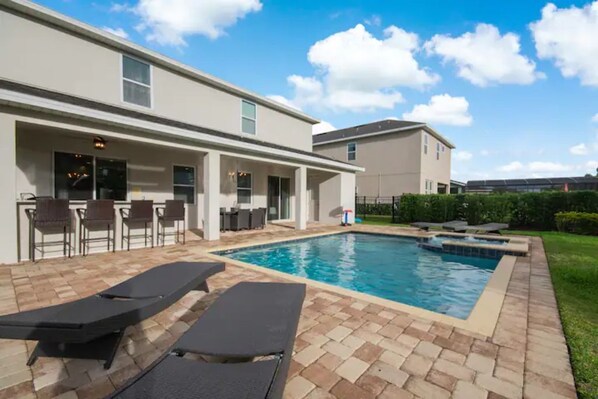 A modern building with a swimming pool, outdoor seating, and a well-maintained lawn.