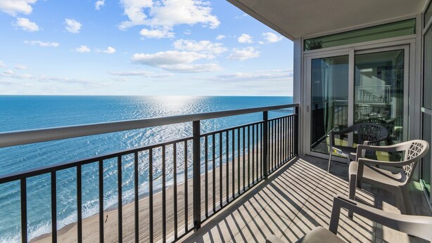 A balcony with a view of the ocean, a glass door, and two chairs. - Oceanfront penthouse, centrally located, 4 bed/ 4 bath (Myrtle Beach)