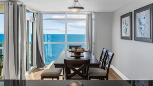 A dining area with a view of the ocean, a table with chairs, and framed artwork on the wall. - Oceanfront penthouse, centrally located, 4 bed/ 4 bath (Myrtle Beach)