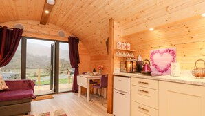 A cozy wooden cabin with a dining area, kitchen, and a large window offering a scenic view. - Lovies Place - Crossgate Luxury Glamping (Penrith)