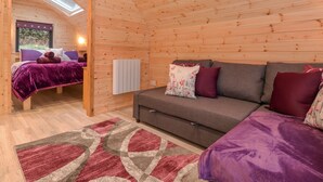 A cozy cabin room with a bed, sofa, and a skylight. - Lovies Place - Crossgate Luxury Glamping (Penrith)