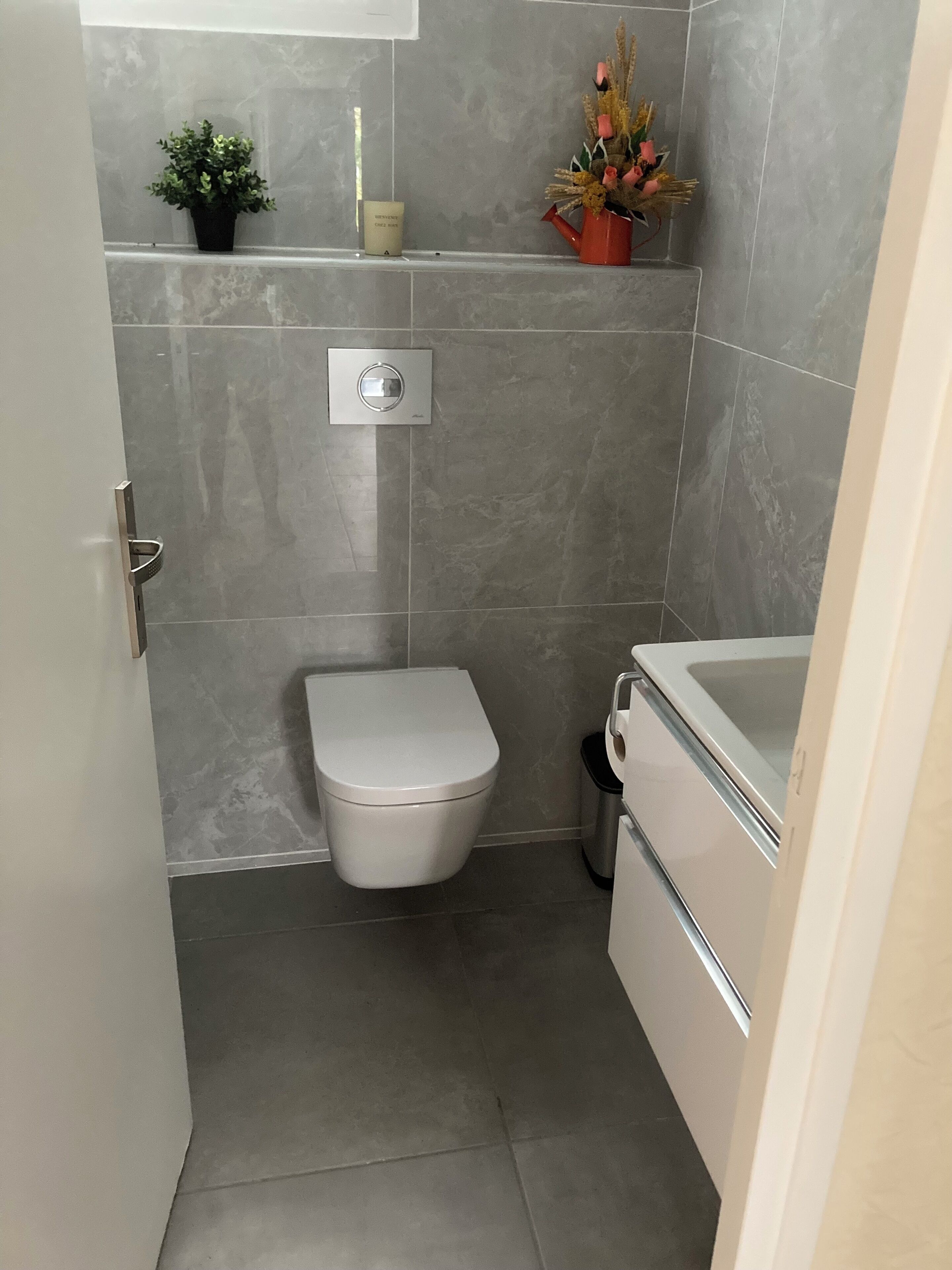 Une salle de bain moderne équipée de toilettes, d’un bidet et d’un petit lavabo.