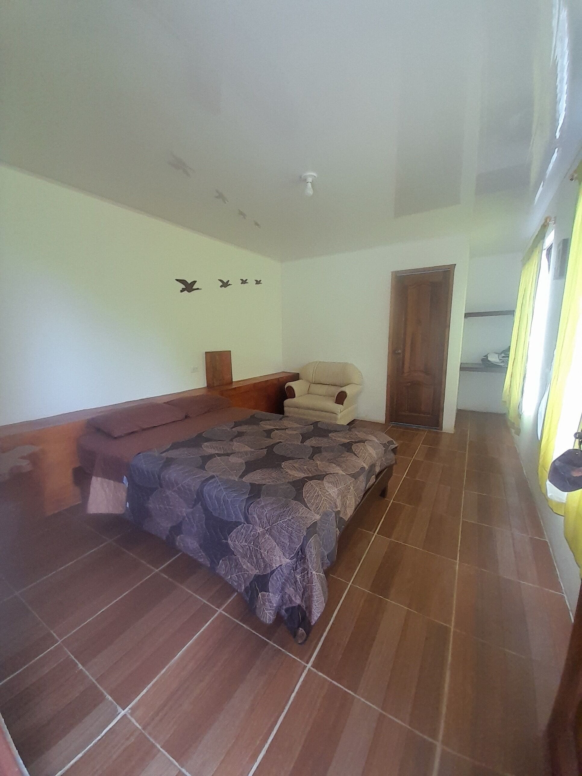 Un dormitorio con cama, un banco, una silla, un armario y una puerta.