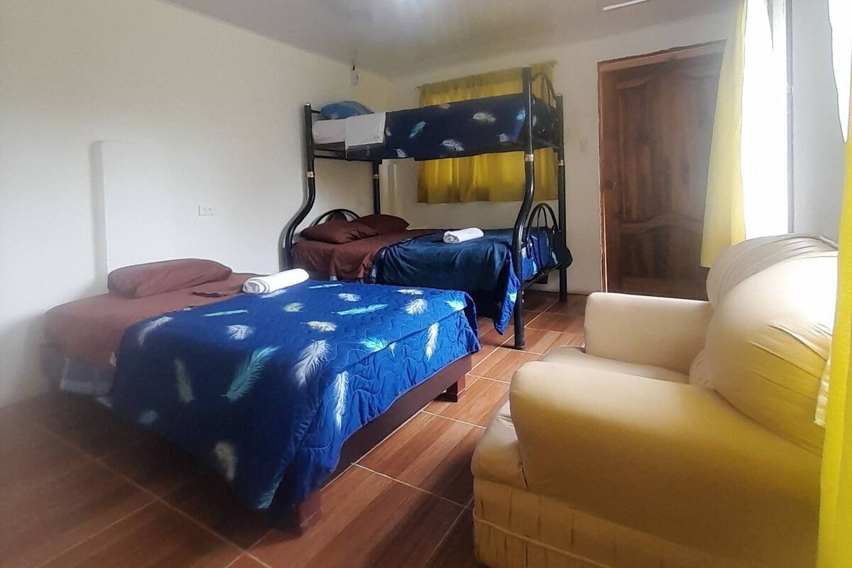 A room with two bunk beds, a yellow armchair, and a window with curtains.