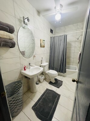Enjoy a clean and functional bathroom with a pedestal sink, bathtub, and shower curtain.