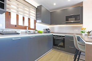Una cocina moderna con armarios grises, horno integrado y microondas.