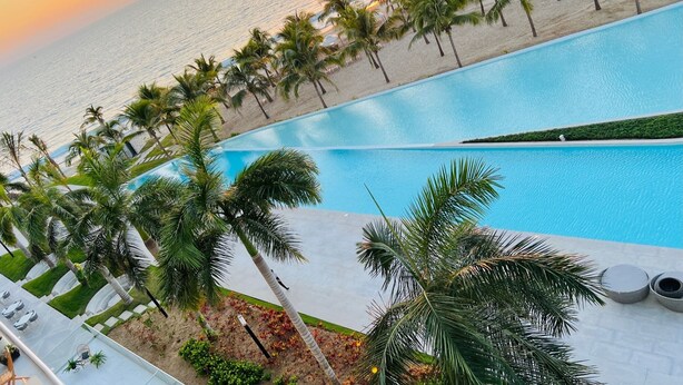 A swimming pool with a view of the ocean and palm trees. - Beachfront 3BR-3BA SunsetParadise (Flamingos)