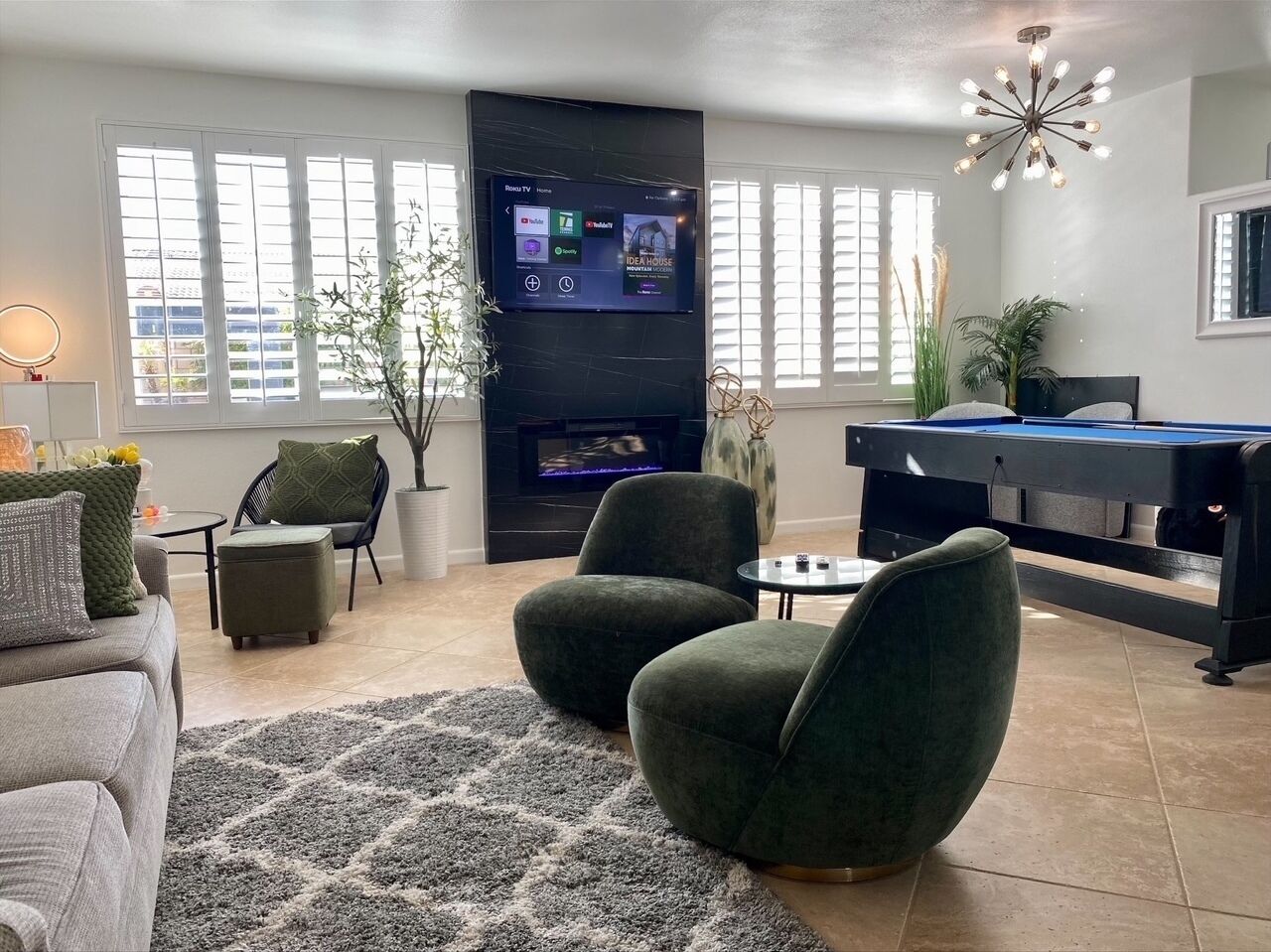Uma sala de estar moderna com televisão de tela plana, assentos confortáveis, mesa de bilhar e lareira.