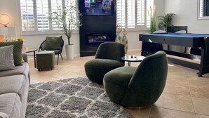 En moderne stue med et fladskærms-tv, behagelige siddepladser, et billardbord og en pejs.