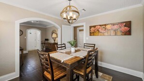 A dining area with a wooden table, chairs, a chandelier, and a painting on the wall. - Newly Remodeled 3BR in Town · Cherry Street (Van Buren)