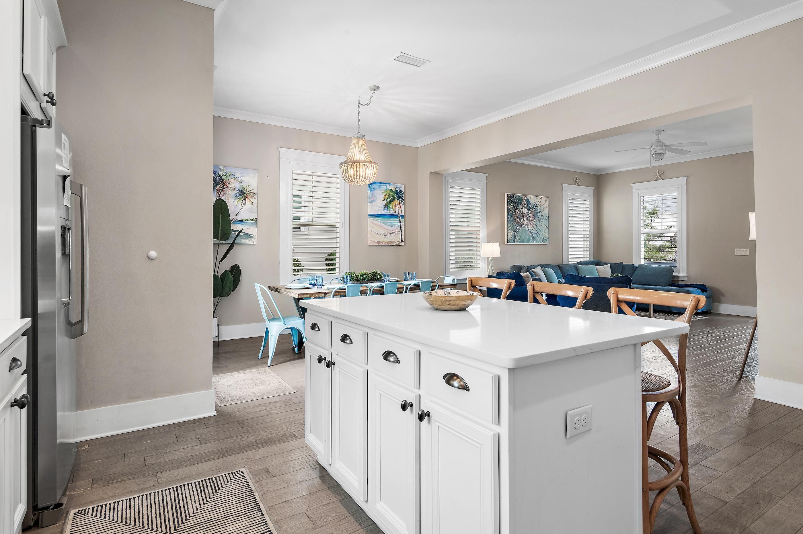 A spacious kitchen with a central island, white cabinetry, and a modern pendant light.