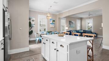 A spacious kitchen with a central island, white cabinetry, and a modern pendant light.