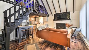 Un espacio habitable moderno con escalera, chimenea, comedor y cocina.