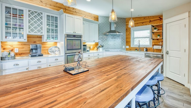 Una cocina moderna con armarios de madera, una isla central, iluminación colgante y un horno empotrado.