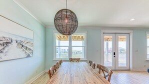 Een eethoek met een houten tafel en stoelen, een hanglamp en een groot raam met uitzicht.