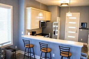 A modern kitchen with a bar area, stainless steel appliances, and pendant lighting.
