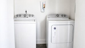 Ein Waschraum mit zwei weißen Whirlpool-Waschmaschinen und einem Trockner, einem an der Wand montierten Seifenspender und einer Steckdose.