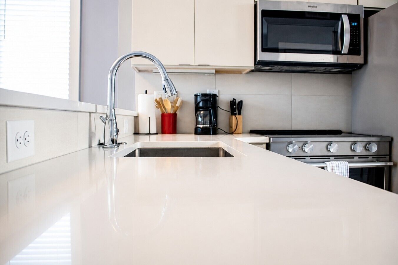 A modern kitchen with a stainless steel sink, a microwave, and a stove.