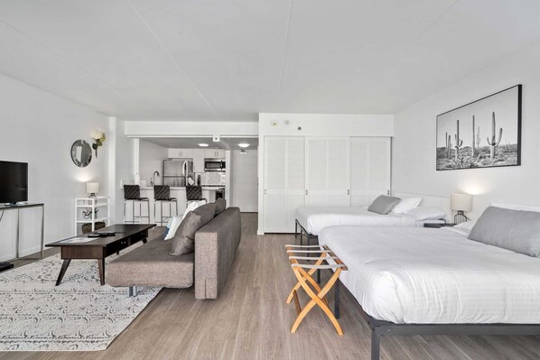 A modern, well-lit apartment with a living area, kitchenette, and a bedroom.