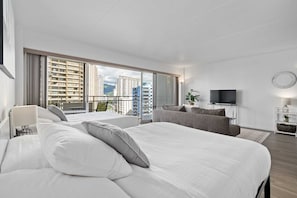Relax in a stylish room with a large bed, sofa, and flat-screen TV, offering a view of the city and mountains.