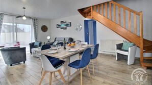 Un salon moderne comprenant un coin repas, un escalier et une vue sur l’extérieur.