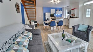 Un appartement moderne comprenant un salon, un coin repas, une cuisine et un escalier.