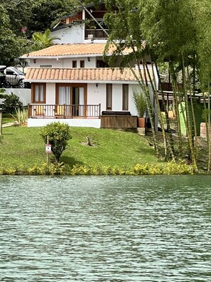 Una casa de dos pisos con balcón, ubicada junto al agua.