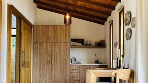 Eine rustikale Küche mit Holzausbau, Fliesenboden, einem Holzespeisesaal mit Stühlen und einer Pendelleuchte.