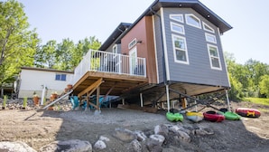 Une maison à deux étages dotée d’une terrasse en bois et d’un petit escalier menant à un balcon.