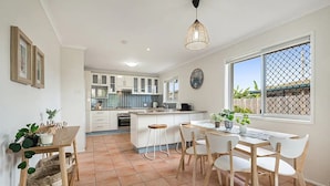 A modern kitchen with white cabinets, a large island, and a dining area with a table and chairs.