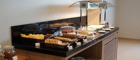 Mostrador de buffet con diversas opciones de comida y una estación de café.