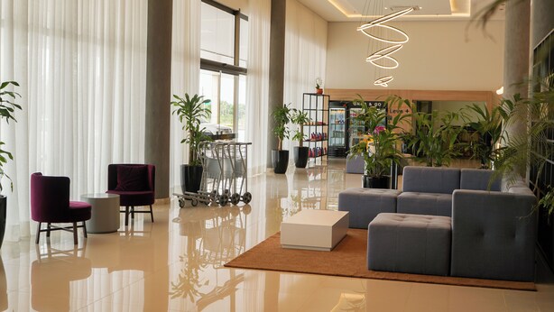 Een ruime lobby met een modern design, met een zithoek met banken en stoelen, een salontafel en een grote potplant.