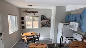 Cozinha moderna com ilha central, eletrodomésticos embutidos e área de refeições com mesa redonda e cadeiras.
