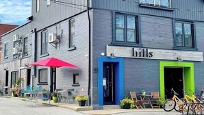 A two-story building with a grey facade, a blue entrance, and a sign that reads "hills". - `Bike` at Hills Meaford | 1BD Suite + Pets (Meaford)