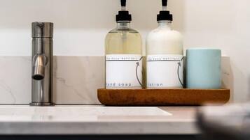 Een badkamer met een moderne kraan, twee zeepdispensers en een blauwe mok op een houten dienblad.