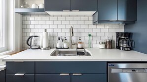 Una cocina moderna con azulejos blancos tipo metro, armarios oscuros y electrodomésticos de acero inoxidable.