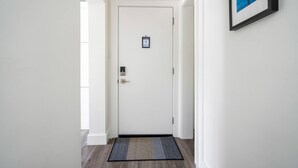 Un couloir avec une porte blanche, un tableau encadré au mur et un tapis à motifs sur le sol.