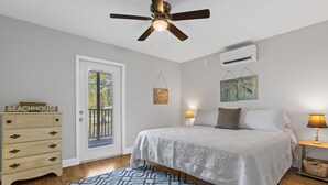 Ein Schlafzimmer mit Bett, Deckenventilator, Kommode, Tür und Fenster.