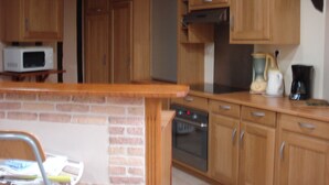 Een keuken met houten kastjes, een magnetron, een oven en een koffiezetapparaat.