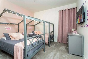 A bedroom with a canopy bed, a desk, a cabinet, and decorative elements like a crown and butterflies. - Modern 9BR Family Villa | Disney Pool and Relax (Kissimmee)
