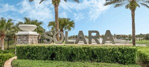 Een aangelegd gebied met de tekst 'SOLARA' duidelijk zichtbaar, omgeven door palmbomen en een heldere lucht.